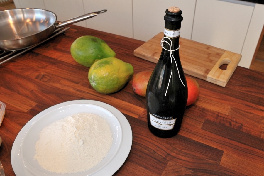 Arbeitsplatte in dunklem Holz mit einem Teller, einer Flasche und Obst. 