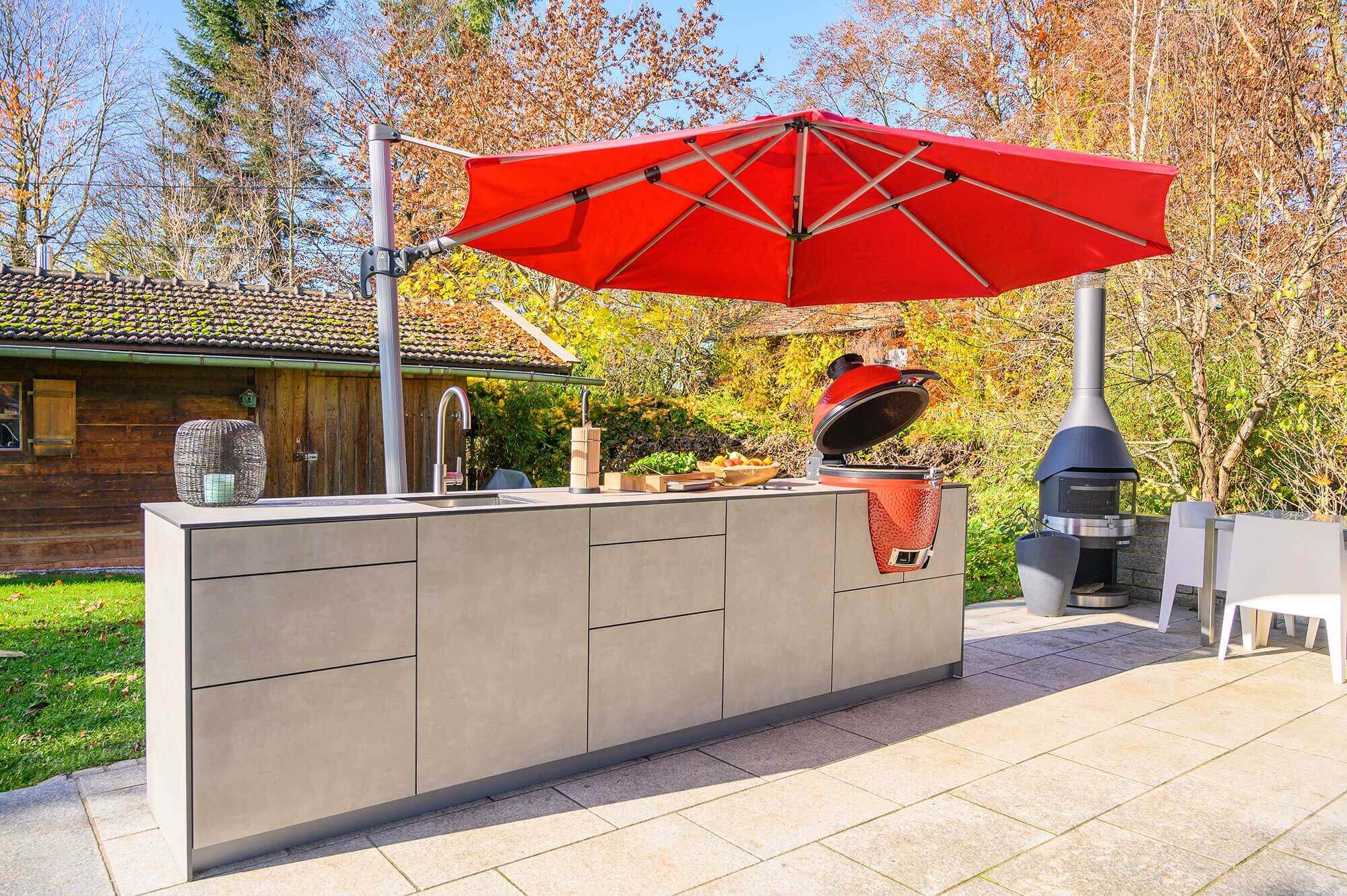 Küchenzeile auf Terrasse unter rotem Sonnenschirm