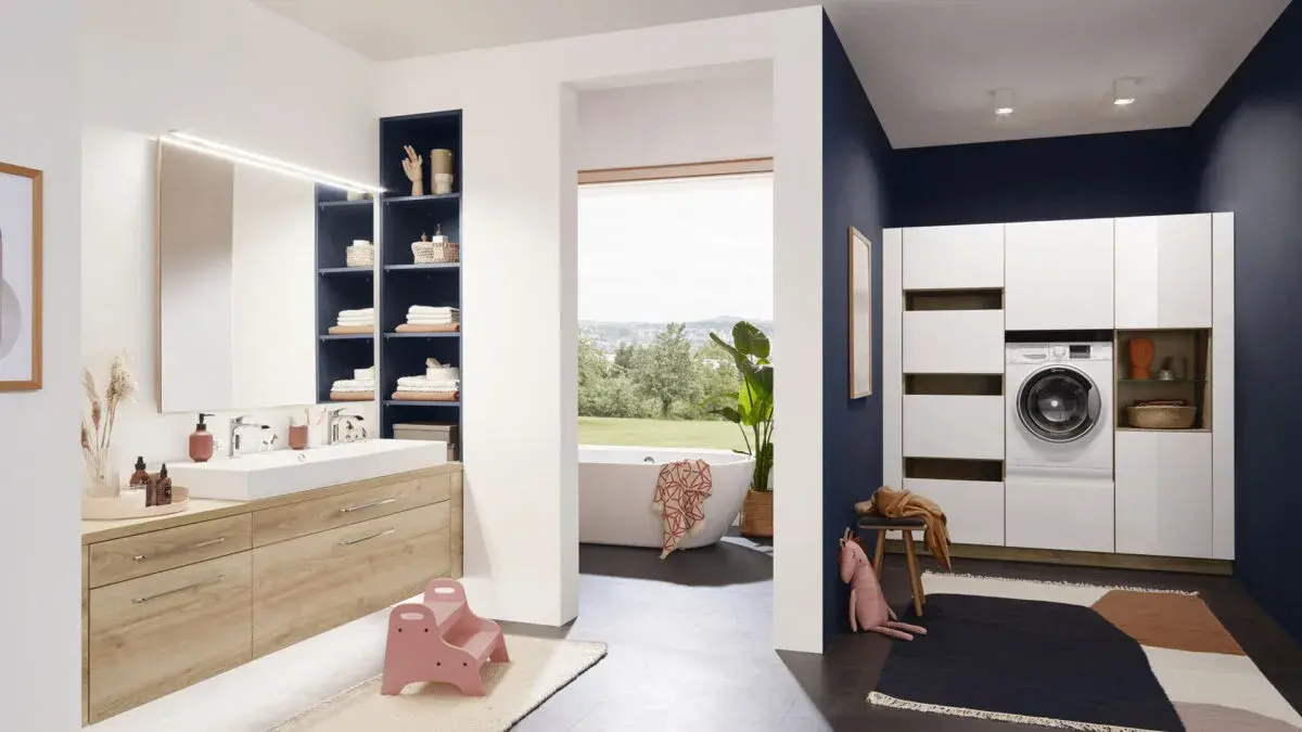 Modernes Badezimmer mit Holzwaschtisch, Regalen, freistehender Badewanne und Waschmaschine.