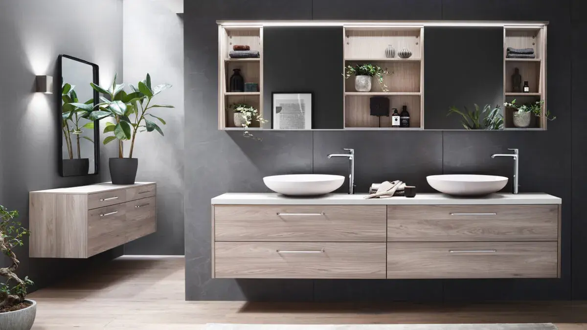 Modernes Badezimmer mit Doppelwaschbecken, hellen Holzmöbeln und grünen Pflanzen.