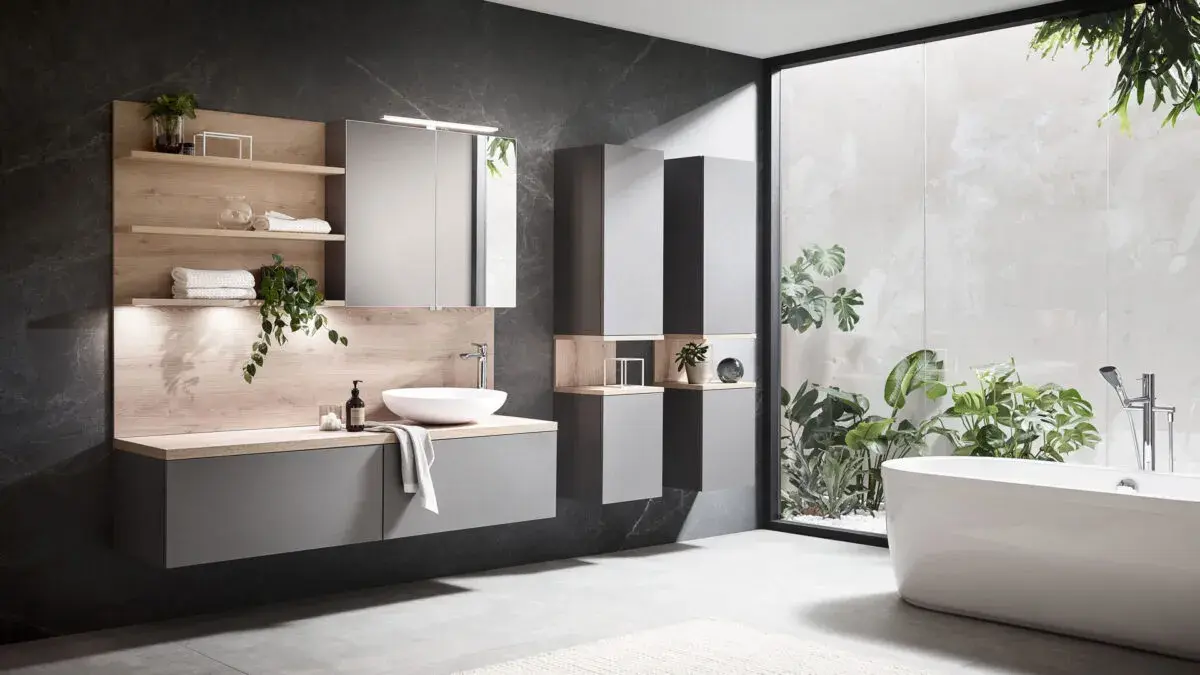 Modernes Badezimmer mit freistehender Badewanne, großem Fenster und grauen Möbeln.