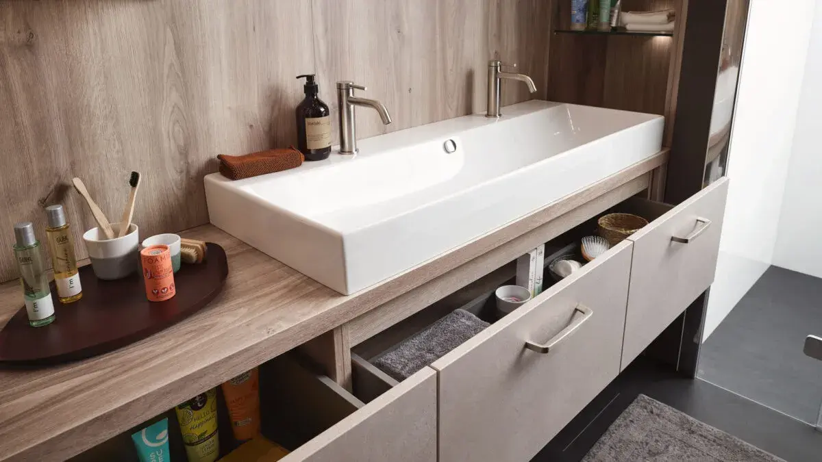 Modernes Badezimmer mit Doppelwaschbecken, Holzschränken und Pflegeprodukten.