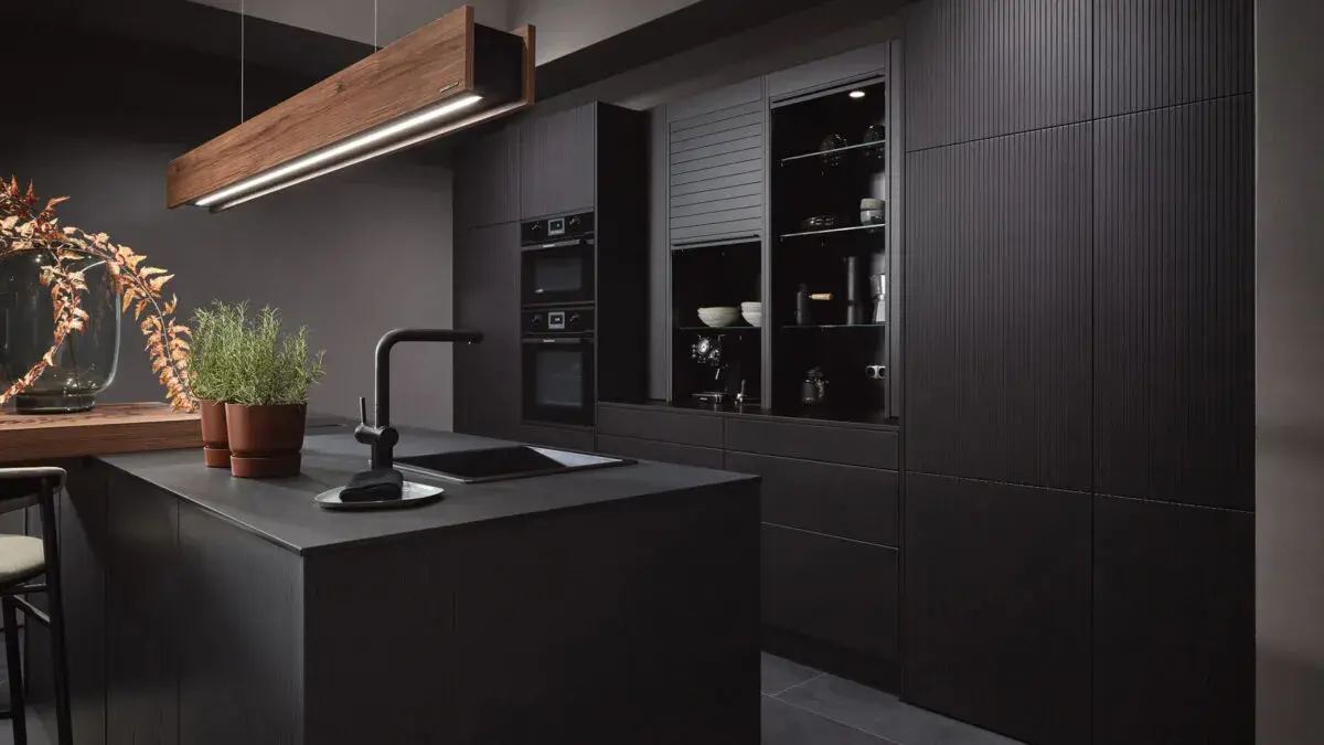 Moderne, dunkle Küche mit Insel, Kräutertöpfen und stilvoller Beleuchtung.