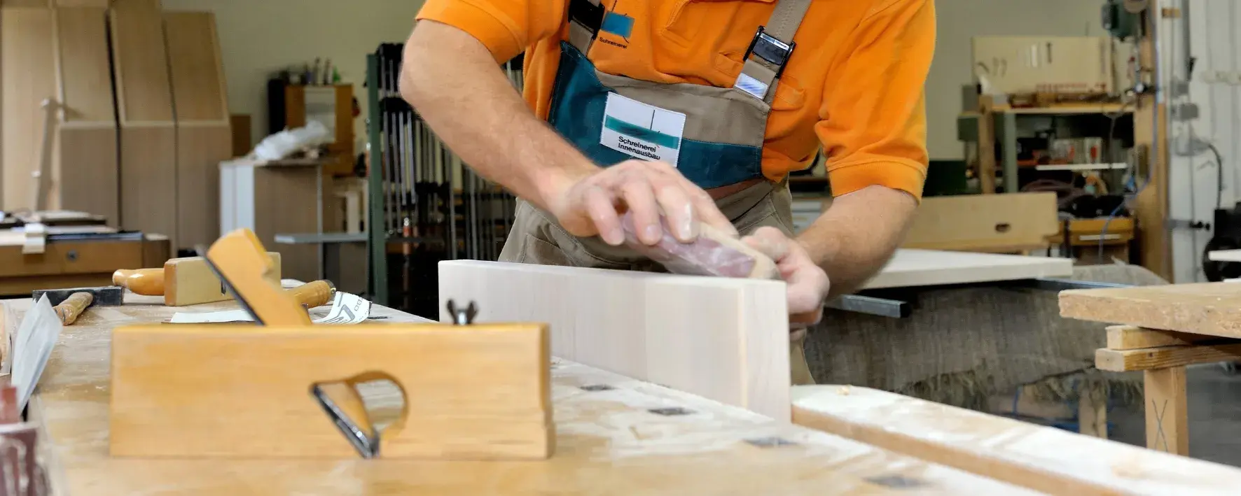 Tischler bearbeitet Holzstück mit einem Hobel