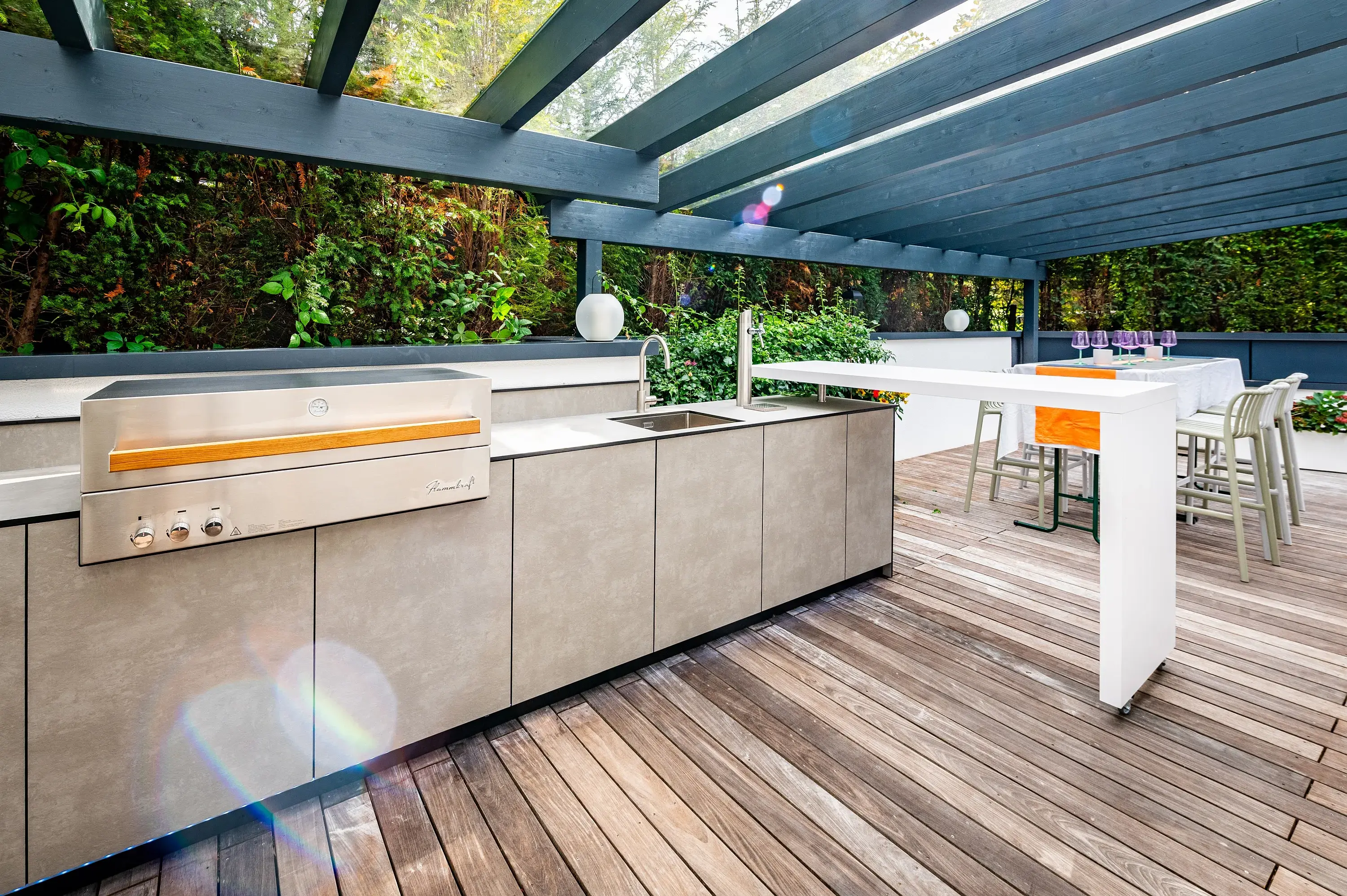 Küchenzeile mit Grill und Theke auf überdachter Dielenterrasse